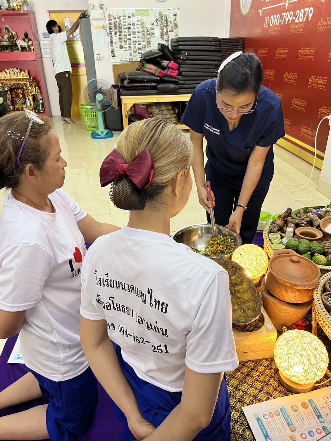 The teacher demonstrates mixing herbs for postpartum compress and steam